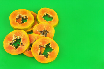 Sliced papaya fruit on green background with copy space for text