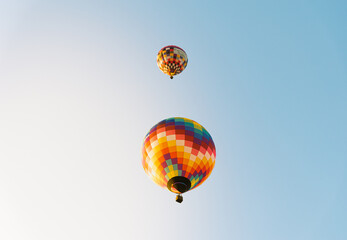 Two very colorful hot air balloons flying on top of each other with a blue sky at the European...