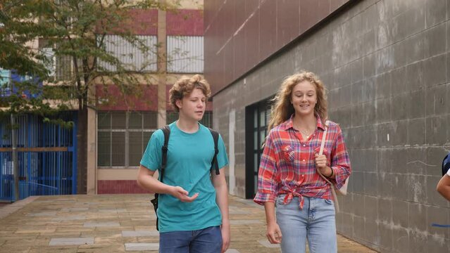 Teenager boy and girl going home after classes in school and having conversation. 