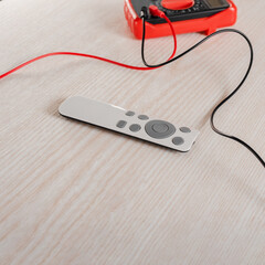 Electric tester multimeter with remote control on wooden background