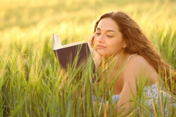 Woman reading a book relaxing in a wheat field