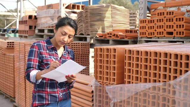 Woman manager keeps records of building materials in the open area of a construction store