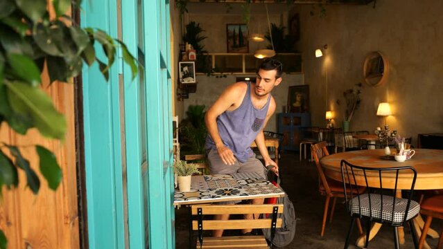 Caucasian Male Tourist Taking Backpack Off Before Sitting Down At Cafe Table In Nicosia. Slow Moiton