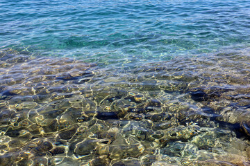 Transparent sea surface with stones on a bottom. Turquoise water for background