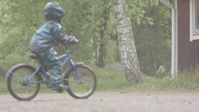 EXTREME WEATHER, SLOMO - A young child riding their bike in heavy rainfall