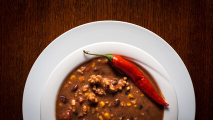 plate of chili with beef over wooden table. view from top