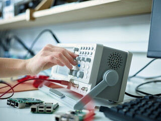 Hand of technician adjusting oscilloscope in electronic laboratory