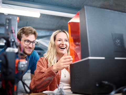 Happy technicians looking at SLA printer in workshop