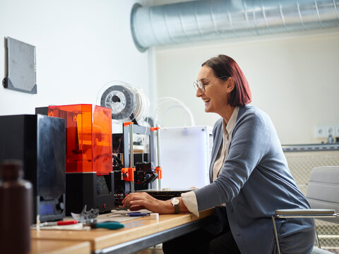 Happy technician operating SLA printer at workshop