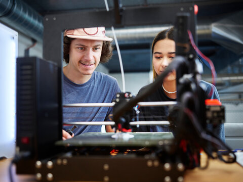 Engineer and colleague operating 3d printer working at workshop