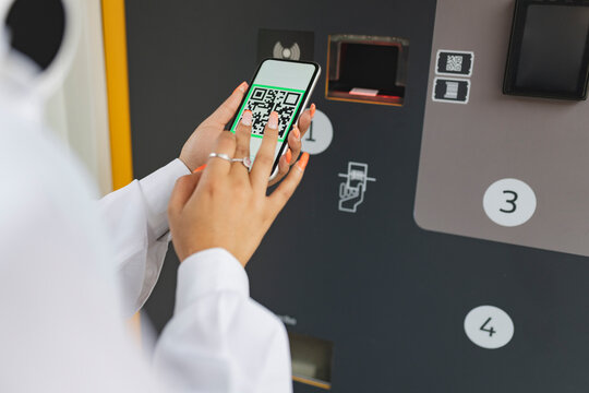 Woman Scanning QR Code Through Smart Phone Near Ticket Vending Machine