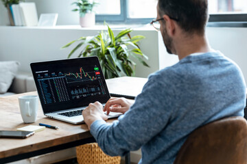 Businessman analyzing stock data on laptop at home