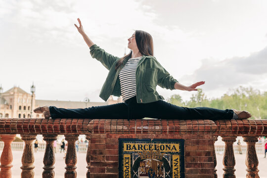 Ballet dancer practicing splits on railing at Plaza de Espana in Spain