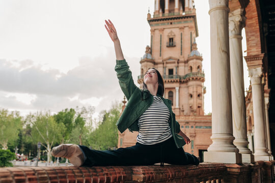 Ballet dancer doing splits on railing at Plaza de Espana in Spain