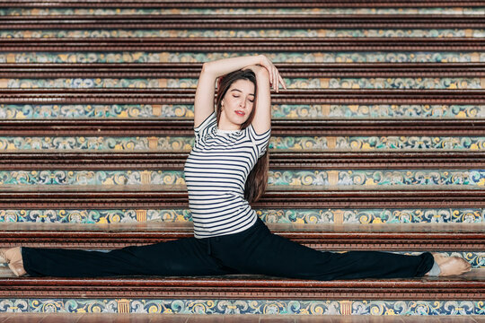 Woman with arms raised doing splits on staircase at Plaza de Espana