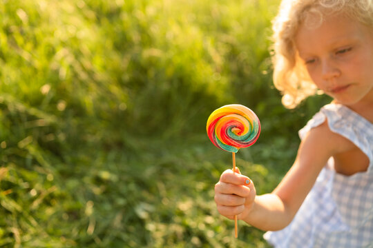 Girl holding rainbow lollipop on sunny day