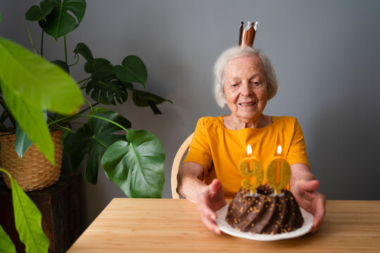Smiling senior woman celebrating birthday with cake at home