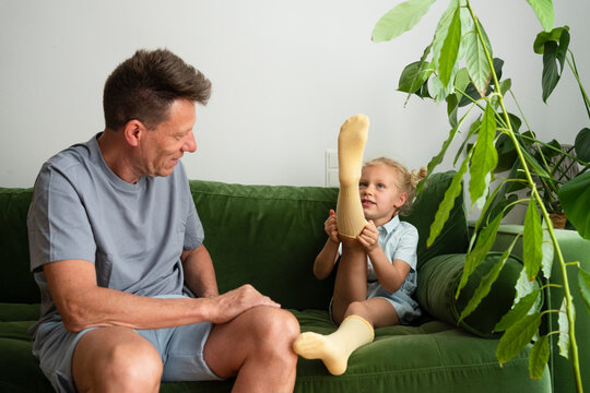 Man looking at daughter wearing socks sitting on sofa