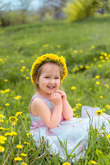 Girl in a meadow in a wreath of dandelions