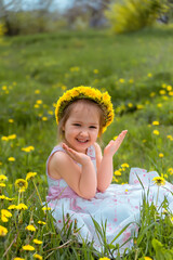 Girl in a meadow in a wreath of dandelions