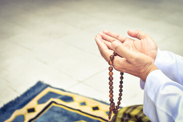 Muslim man in white session lift two hand for praying and wearing bead on hand to determine the...