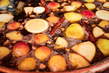 Bowl of traditional English hot spicy mulled wine with cloves, cinnamon sticks, dried fruit and red wine on sale at Bath Christmas market.