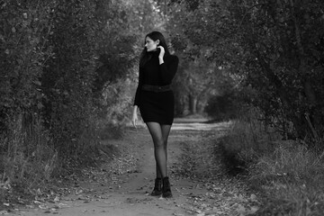 Woman in black standing on a road in the forest in black and white