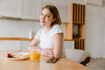 Obraz na płótnie Canvas Smiling young woman having healthy breakfast