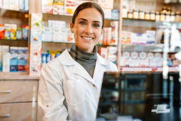 Rolgordijnen White apothecary smiling while working with till at pharmacy © Drobot Dean