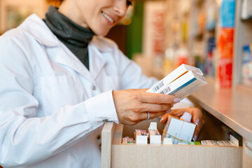 White apothecary wearing lab coat smiling while working in pharmacy