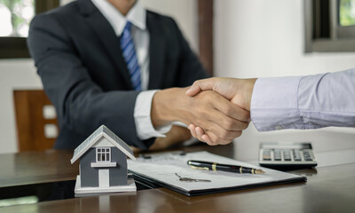 Businessmen and brokers real estate agents shake hands after completing negotiations to buy houses...