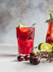 Cocktail or lemonade with cherries and lime, grey background. Mocktail. Cold summer drink.