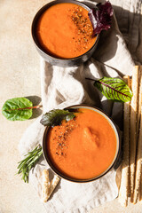 Fresh tomato gazpacho with ground pepper, greens and grissini or bread sticks. Direct sunlight and hard shadows.