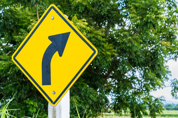 Warning traffic sign yellow turn right board on the road with cloud and blue sky.