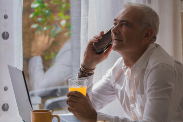 Fototapeta premium adult man talking on mobile phone while having breakfast at home