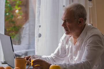 adult man using pc while having breakfast at home