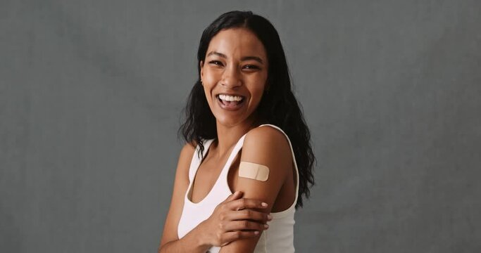 Young mixed race female gently touching her arm with band aid