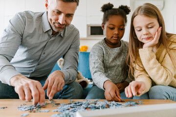 Adopted african little girl solving puzzles with father and sister