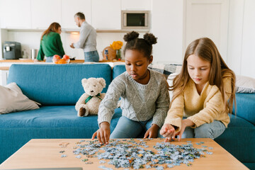 Adopted sisters solving puzzles sitting on couch
