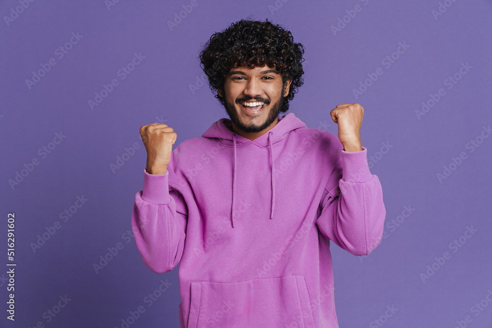 Wall mural portrait of young indian handsome curly celebrating man rasing fists