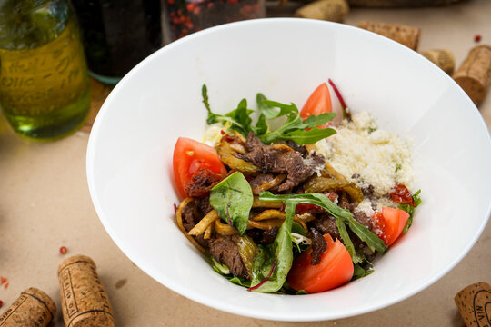warm salad with beef, tomatoes and Parmesan cheese, macro photo
