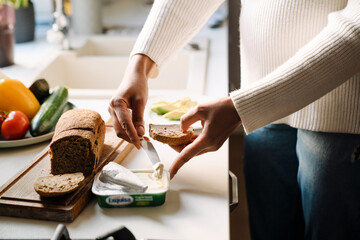 Female hands taking cream cheese to spread it on bread