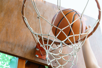close view of hands throwing a ball into a basketball hoop, teenage boy playing at home in the backyard, outdoor activities on summer vacation