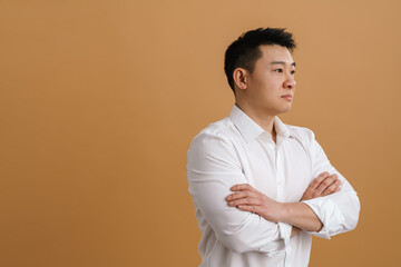 Brunette adult asian man wearing shirt standing with arms folded