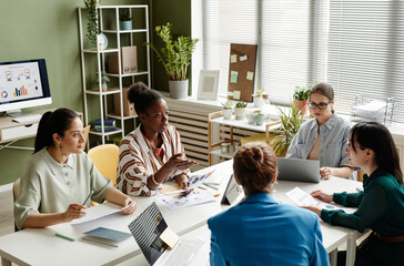 Group of female coworkers planning work in team at table during business meeting