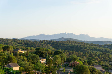 Fototapeta na wymiar View of the houses in the forest of the town of Talamanca in Bages and the mountains of Montserrat in the background