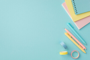School supplies concept. Top view photo of colorful stationery note pads adhesive tape and pens on isolated pastel blue background with copyspace