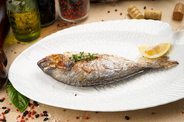 baked fish on a white plate with lemon
