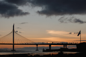 View of the span of the cable-stayed bridge against the backdrop of the sun setting behind the horizon.