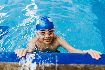 latin child boy swimmer wearing cap and goggles in a swimming training at the Pool in Mexico Latin America	